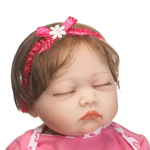 Poupée bébé Reborn réaliste avec cheveux bruns et bandeau rose à pois sur fond blanc