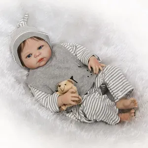 Poupée réaliste Reborn en tenue rayée avec un ours en peluche sur fausse fourrure blanche