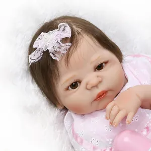 Realistic reborn baby doll with brown hair and pink floral outfit on soft plush background