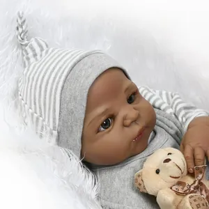 Poupée Reborn réaliste à peau foncée portant un bonnet gris et un ours en peluche