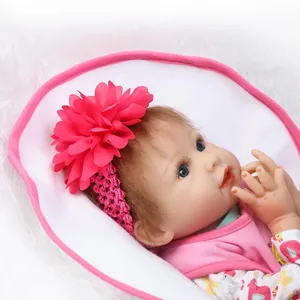 Realistic reborn baby doll with blue eyes, brown hair and floral headband on white plush