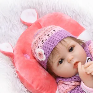 Poupée bébé reborn réaliste en tenue crochet rose sur un oreiller en peluche