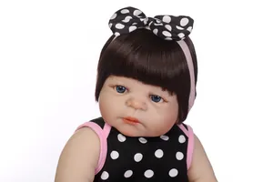 Close-up of reborn baby doll with blue eyes, brown hair and polka dot headband