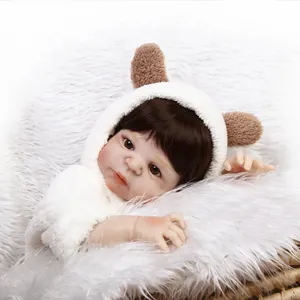 Realistic newborn reborn baby doll in plush hooded outfit with bear ears on white fur