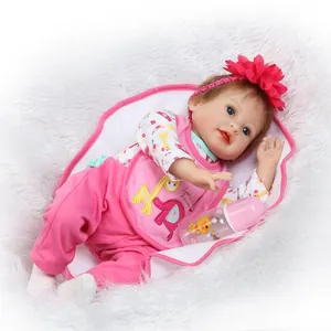 Lifelike reborn baby doll in pink floral outfit with feeding bottle on plush blanket
