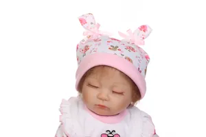 Close-up of lifelike baby doll wearing floral hat with bunny ears and pink bow detail