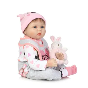 Lifelike reborn baby doll with blue eyes wearing pink knit outfit and plush bunny