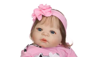Close-up of reborn baby doll featuring blue eyes, long eyelashes and pink floral headband