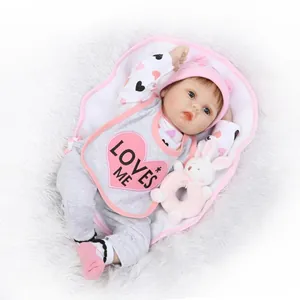 Realistic reborn baby doll in grey outfit with pink bib and bunny toy on plush rug