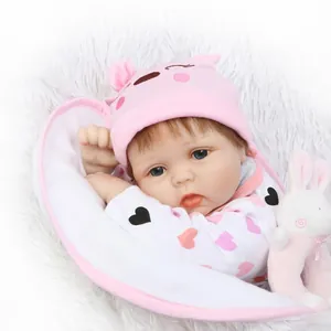 Realistic newborn baby doll wearing pink knit hat and heart pattern romper with bunny toy
