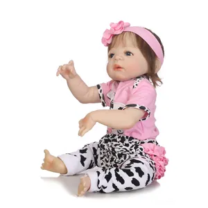 Lifelike reborn baby doll in pink cow print outfit with blue eyes and brown hair
