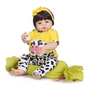 Poupée bébé Reborn réaliste avec cheveux bruns et tenue motif vache sur coussin vert