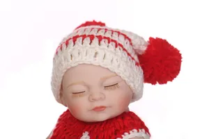 Close-up of lifelike baby doll features with red and white striped knit pom-pom hat