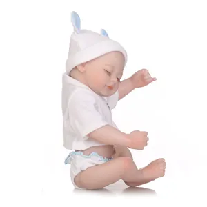 Realistic reborn baby doll in white outfit and blue trimmed hat on white background