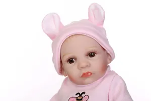 Détail d'une poupée réaliste avec bonnet de lapin rose et broderie d'abeille
