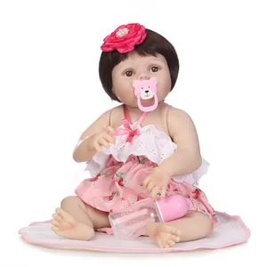 Poupée bébé reborn réaliste en robe à fleurs roses avec tétine et biberon sur blanc