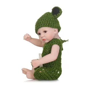 Realistic reborn baby doll in green crochet outfit with hat on a white background