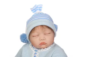 Gros plan d'une poupée Reborn endormie avec traits fins et tenue en tricot bleu pastel