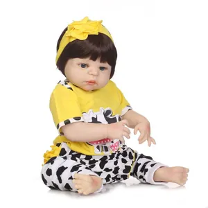 Poupée bébé réaliste en haut jaune et pantalon à motif vache avec bandeau à fleurs sur blanc