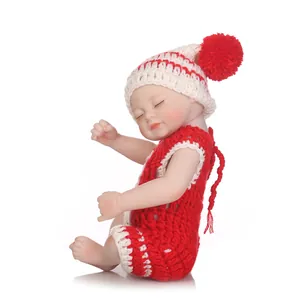 Lifelike sleeping baby doll in red and white knitted outfit on white background