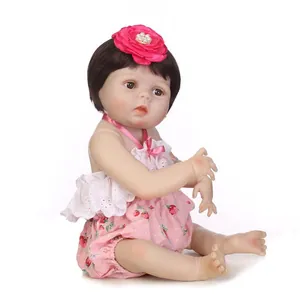 Poupée reborn réaliste aux cheveux bruns avec tenue fraise rose et bandeau fleuri