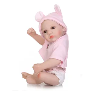 Poupée bébé reborn réaliste avec chapeau lapin rose et tenue sur fond blanc