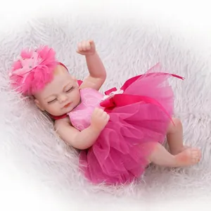 Mini reborn baby doll in pink tutu dress sleeping on soft white plush background