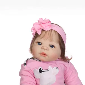 Realistic reborn baby doll in pink cow outfit with floral headband on white background