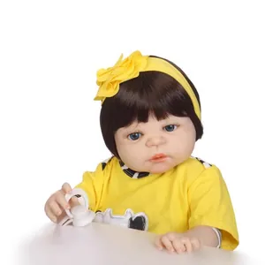 Poupée bébé reborn réaliste en tenue jaune avec bandeau et tétine sur fond blanc pur