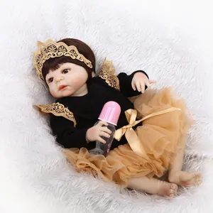 Poupée Reborn avec tutu doré et bandeau couronne sur tapis en peluche blanc avec biberon