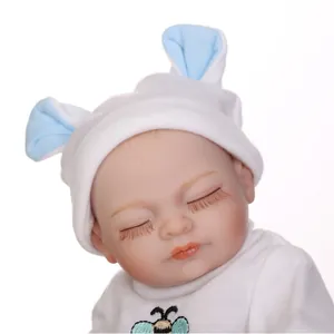 Realistic reborn baby doll in white bee outfit sleeping with closed eyes and blue ears