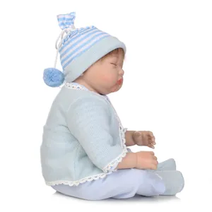 Poupée réaliste Reborn en tenue tricotée bleue dormant paisiblement sur fond blanc