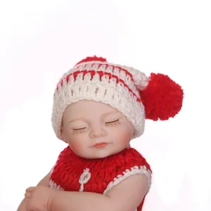Lifelike sleeping reborn baby doll with red knit hat and white pompom on white background