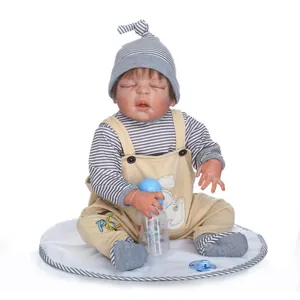 Bambola reborn realistica con vestito a righe, biberon e ciuccio su cuscino bianco