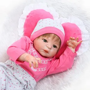 Realistische herboren babypop in roze hartjesoutfit op witte pluchen achtergrond