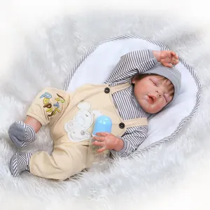 Bambola reborn realistica con completo a righe e salopette beige su tappeto peluche