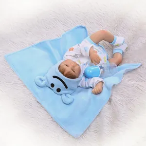 Poupée bébé reborn réaliste dormant dans une couverture bleue douce avec un biberon