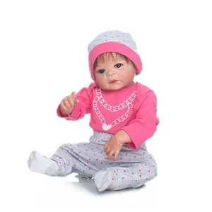 Realistische Reborn-babypop in roze hartoutfit en grijze bloemenbroek op witte basis