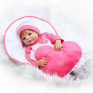 Realistische Reborn babypop in roze outfit met hartkussen op witte pluche achtergrond