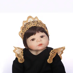Poupée bébé reborn réaliste avec cheveux bruns et bandeau couronne en dentelle dorée sur blanc