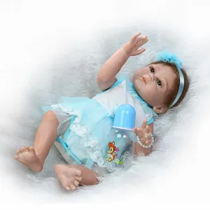 Realistic reborn baby doll in blue lace dress with matching bottle on white plush rug