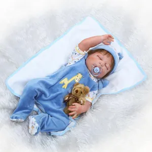 Reborn baby doll in blue velvet giraffe outfit sleeping with a mini teddy bear