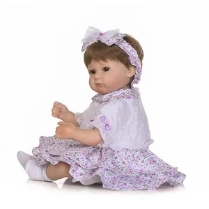 Poupée bébé reborn réaliste avec cheveux bruns et robe fleurie violette élégante