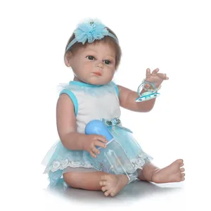 Lifelike reborn baby doll in blue lace dress with bottle and pacifier on white background