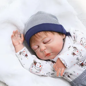 Lifelike reborn baby doll sleeping in cartoon bodysuit with blue knit hat on plush mat