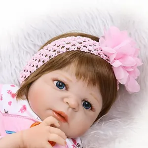 Bambola Reborn realistica con occhi azzurri, fascia con fiori rosa e vestitini per neonati