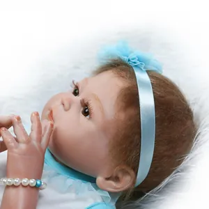Lifelike reborn baby doll with brown curls and blue headband on soft plush background