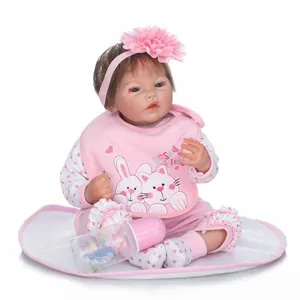 Realistic reborn baby doll in pink polka dot outfit with accessories on a white background