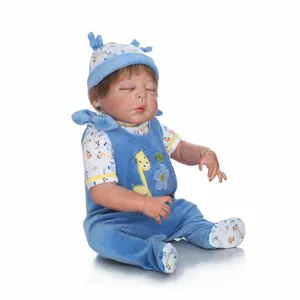 Sleeping reborn baby doll in blue velvet suit with deer hat on white background