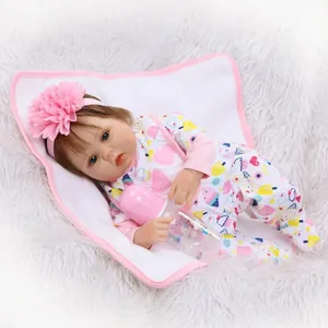 Lifelike reborn baby doll with blue eyes in floral onesie with pink headband and bottle